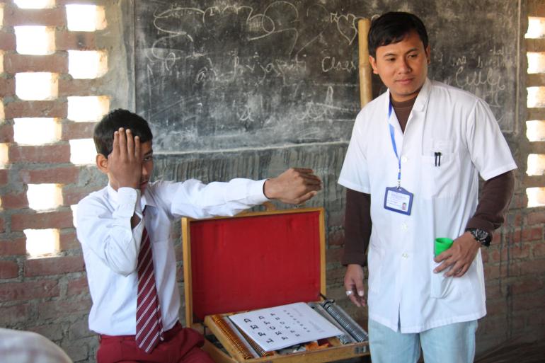 Nepali school boy having eyes screened by eye care professional