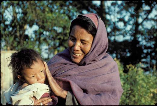Nepali mother smilling and looking at young son while touching his face