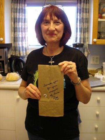 Pat holding up paper bag that reads"thank you for supporting Seva"