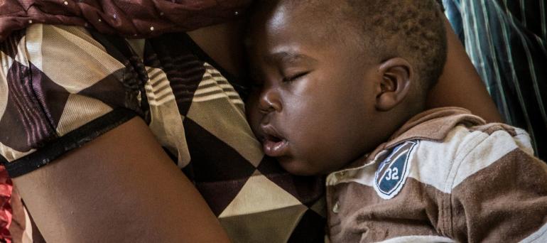 Young Tanzanian boy sleeping in his mother's arms