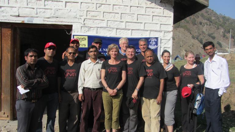 Seva Nepal and Seva Canada team standing in front of building smiling at camera