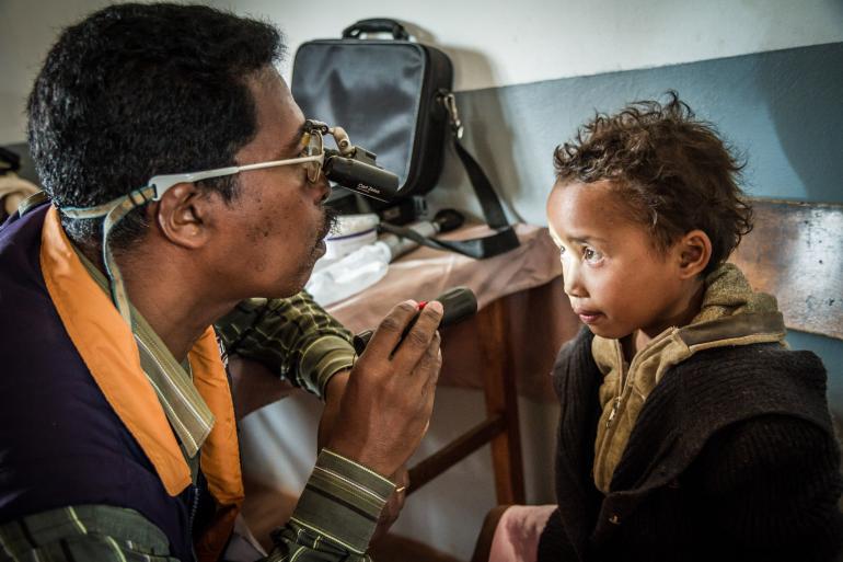 young malagasi boy having eyes examined by doctor