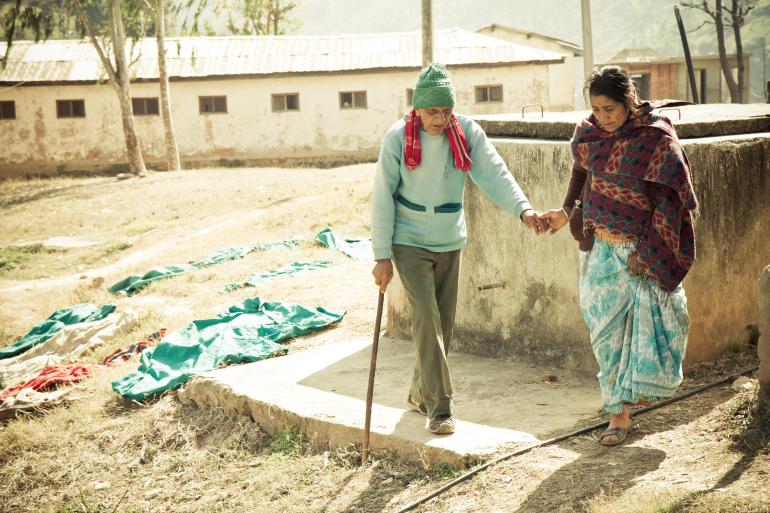 visually impaired nepali man being guided by caregiver