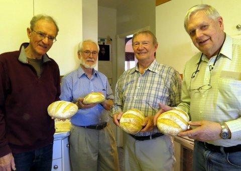 4 men smiling and holding bread they made in Pat's workshop