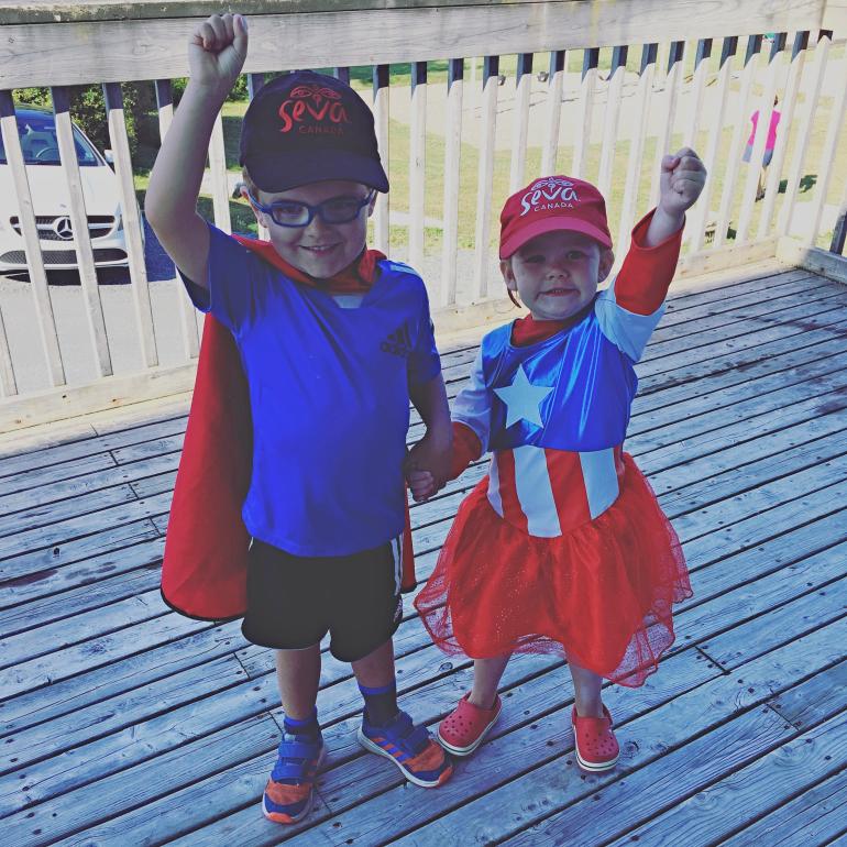 Zachary and Rosalie dressed as superheros with Seva Canada hats
