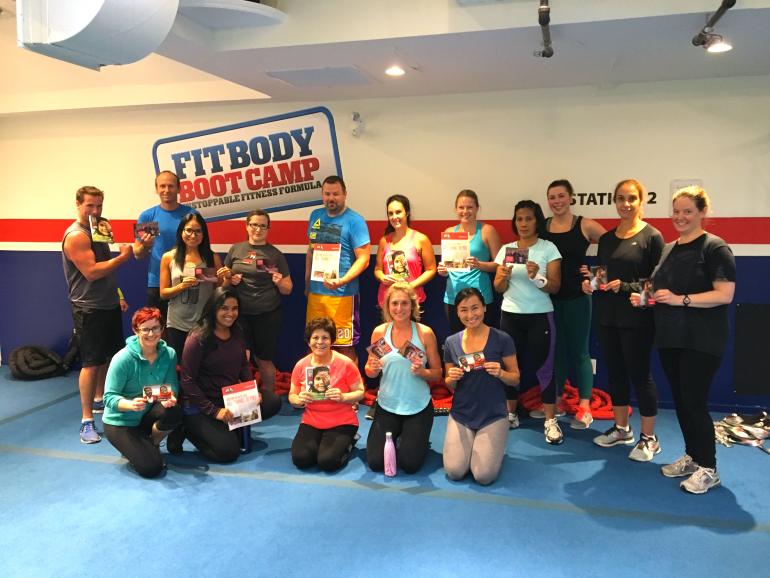 Participants from one of Fit Body's boot camp classes holding up Seva newsletters and GOS catalogues