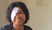 Smiling Cambodian woman with eye patch after cataract surgery