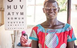 Molly Atim in Uganda standing in front of eye chart